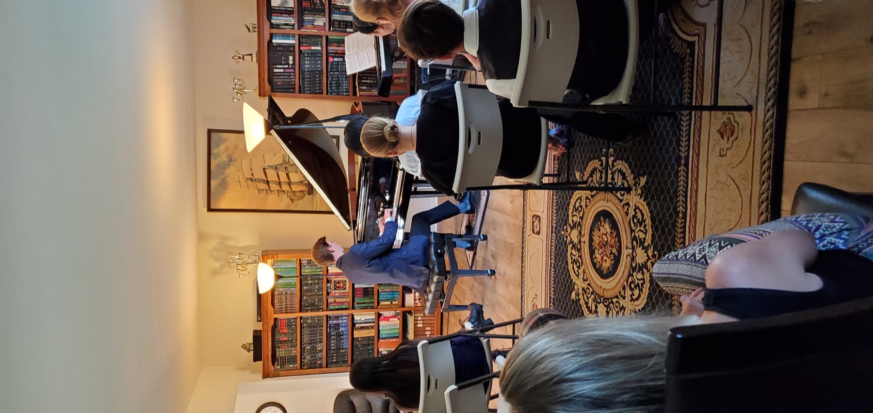 Pianist in formal attire performing at a student concert